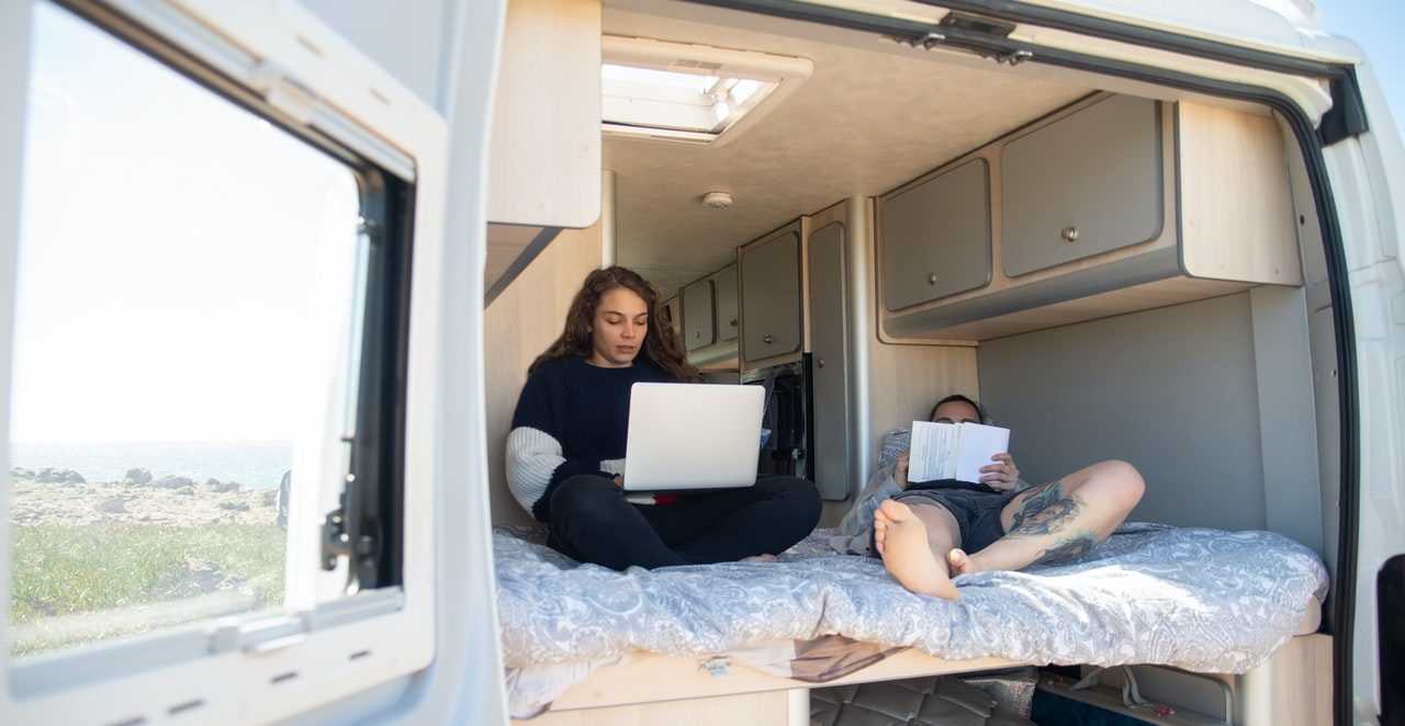 A couple working on laptops in the back of a camper van. Photo by Kampus Production